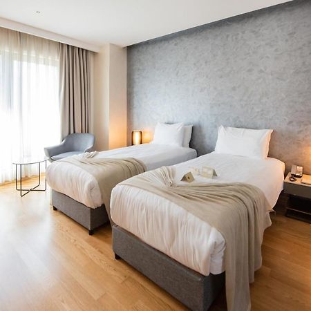 ดอสโซ่ ดอสซี่ โฮเต็ล แอน์ สปา ดาวน์ทาวน์ Hotel อิสตันบูล ภายนอก รูปภาพ The photo shows a modern hotel room featuring two single beds with white linens and soft gray throw blankets. The room has a stylish design, with wooden flooring and a large window dressed with light curtains that allow natural light to enter. There'