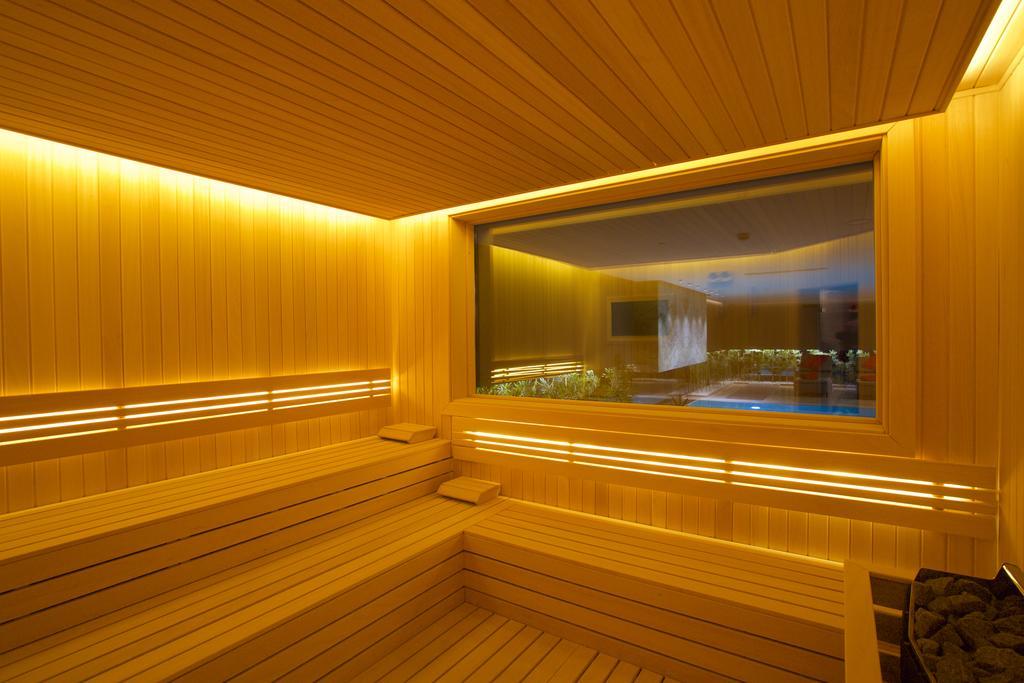 ดอสโซ่ ดอสซี่ โฮเต็ล แอน์ สปา ดาวน์ทาวน์ Hotel อิสตันบูล ภายนอก รูปภาพ The photo depicts a sauna interior characterized by wooden paneling and warm, ambient lighting. The walls and seating are made of light-colored wood, creating a cozy atmosphere. There is a large window that offers a view into another room, possibly f