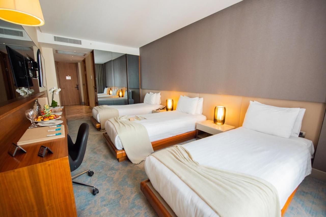 ดอสโซ่ ดอสซี่ โฮเต็ล แอน์ สปา ดาวน์ทาวน์ Hotel อิสตันบูล ภายนอก รูปภาพ The photo shows a modern hotel room featuring two single beds, each with white linens and a light blanket partially draped over them. There are stylish bedside lamps on either side of the beds, providing a warm glow. A wooden desk and chair are posit