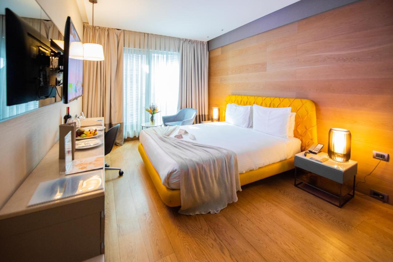ดอสโซ่ ดอสซี่ โฮเต็ล แอน์ สปา ดาวน์ทาวน์ Hotel อิสตันบูล ภายนอก รูปภาพ The photo shows a modern hotel room with a cozy and inviting atmosphere. The room features a large bed with a yellow upholstered headboard, topped with white bedding and a soft gray throw blanket casually draped over it. To the side of the bed is a s