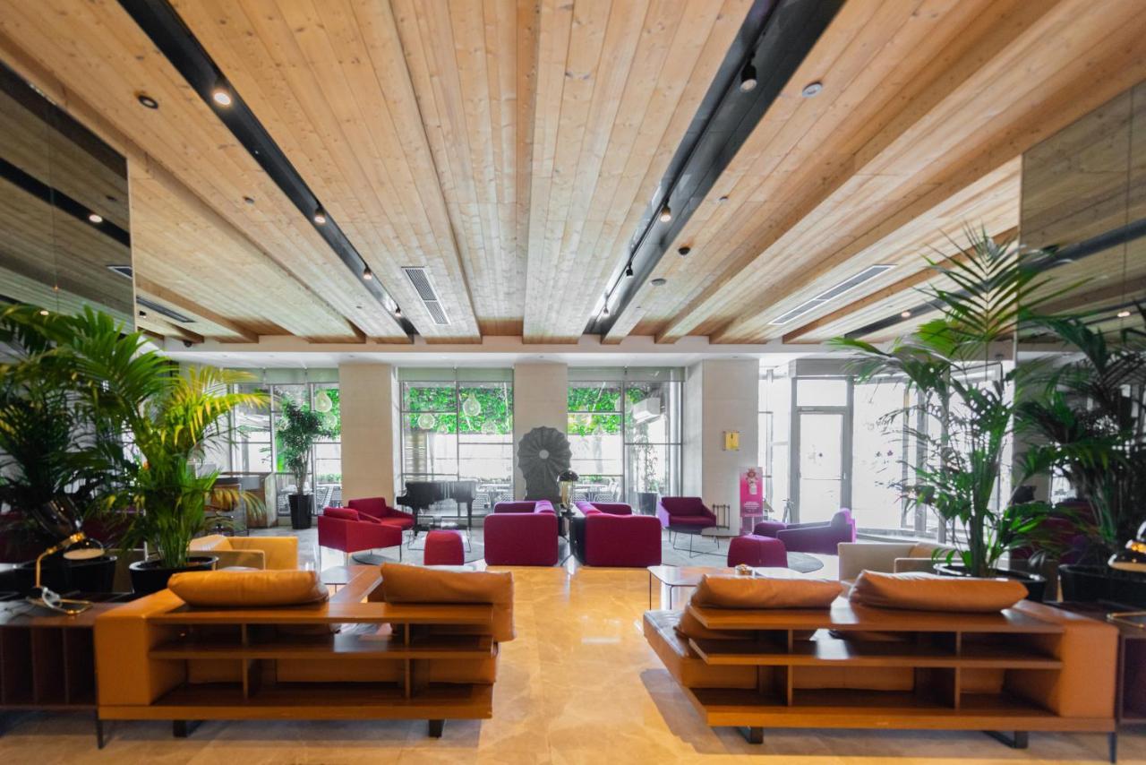 ดอสโซ่ ดอสซี่ โฮเต็ล แอน์ สปา ดาวน์ทาวน์ Hotel อิสตันบูล ภายนอก รูปภาพ The photo shows a modern and spacious lobby area. There are wooden beams on the ceiling, giving the space a warm and inviting atmosphere. The flooring appears to be light-colored stone or tile. 

In the center of the room, there are several seating a