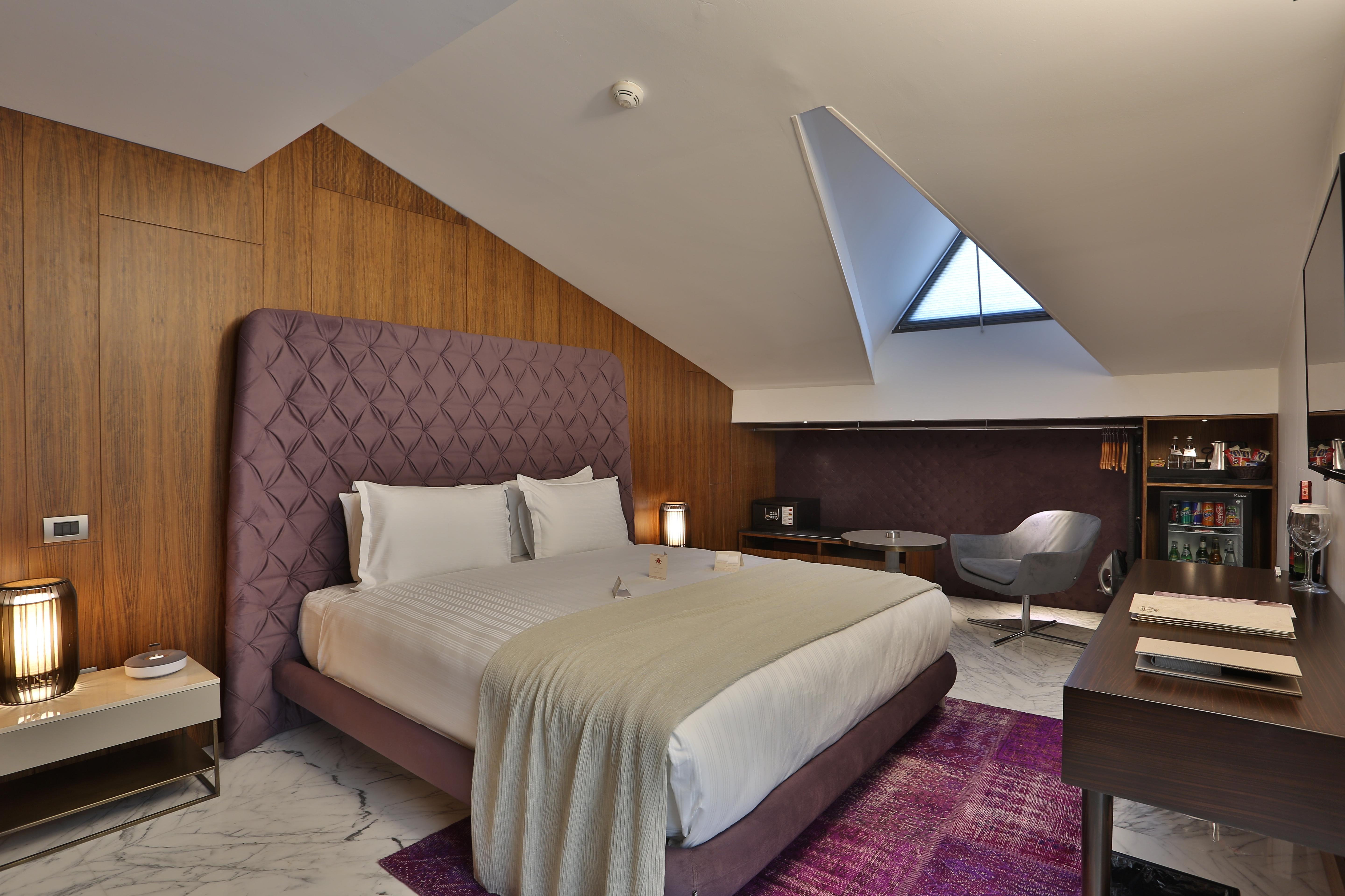 ดอสโซ่ ดอสซี่ โฮเต็ล แอน์ สปา ดาวน์ทาวน์ Hotel อิสตันบูล ภายนอก รูปภาพ The photo shows a stylish hotel room with a modern design. It features a large bed with a tufted purple headboard, complemented by white bedding and a light gray throw. The walls are made of wooden panels, adding warmth to the space. To the side, the