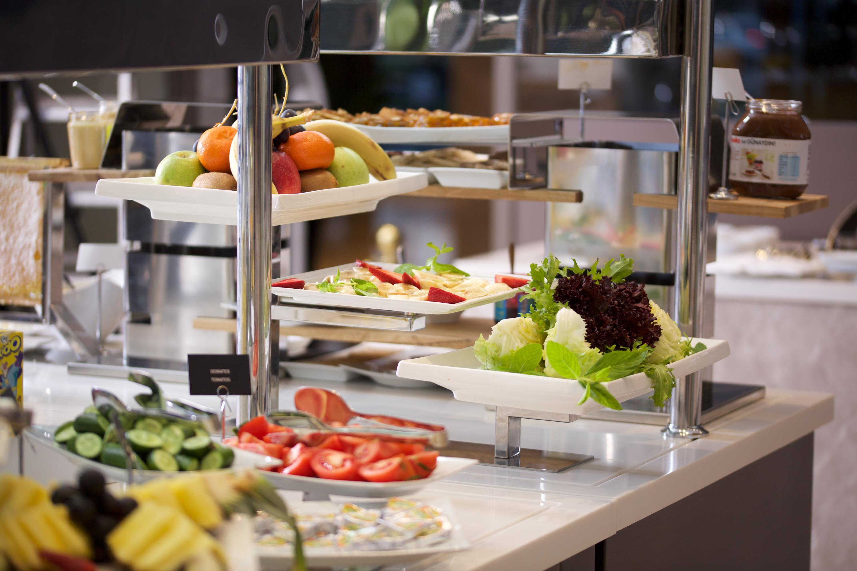 ดอสโซ่ ดอสซี่ โฮเต็ล แอน์ สปา ดาวน์ทาวน์ Hotel อิสตันบูล ภายนอก รูปภาพ The photo depicts a buffet-style setup featuring a variety of fresh food items. There are several trays with colorful fruits, including apples and bananas, positioned on one side. In front, there are plates with vegetables, like sliced tomatoes and l