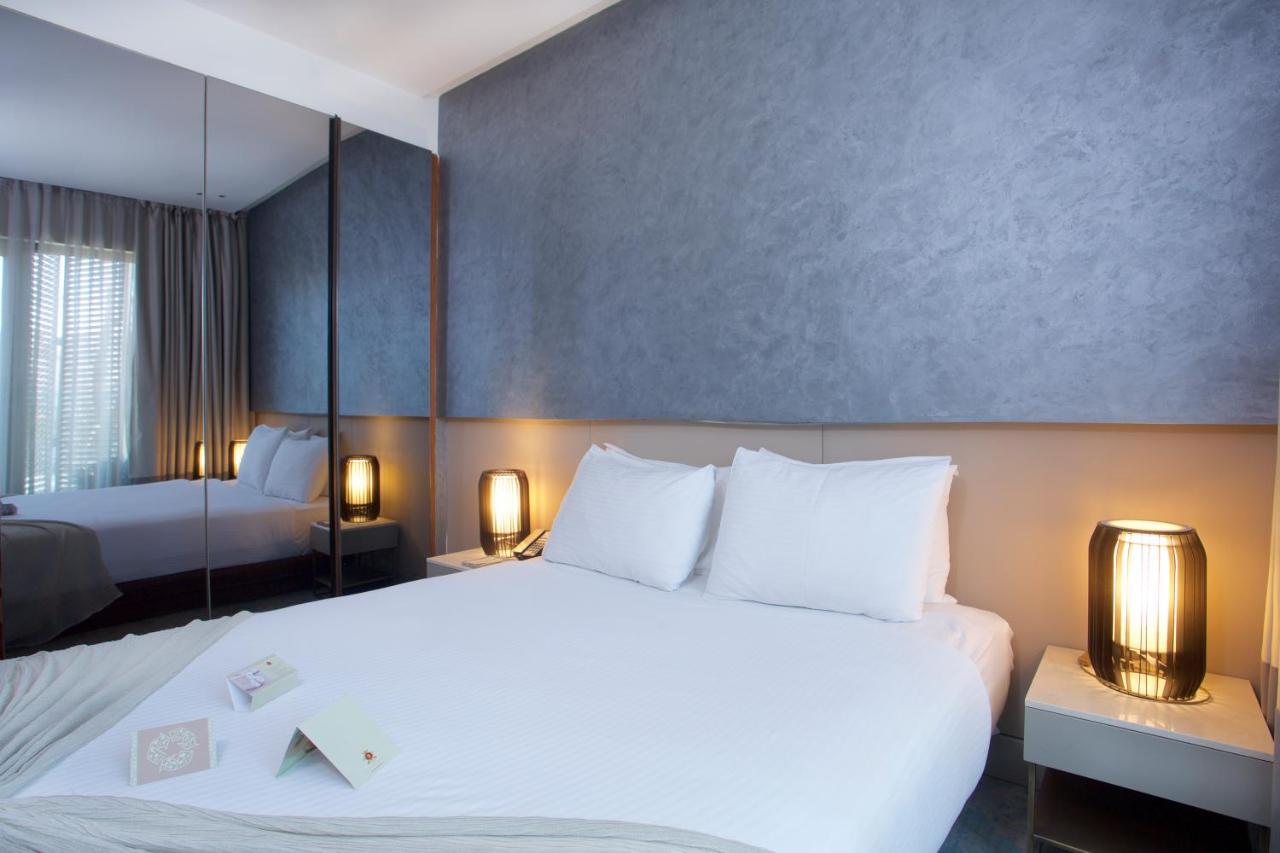 ดอสโซ่ ดอสซี่ โฮเต็ล แอน์ สปา ดาวน์ทาวน์ Hotel อิสตันบูล ภายนอก รูปภาพ The photo depicts a modern hotel room featuring a double bed with white bedding and two pillows. The walls have a smooth, textured finish, and there are large windows with sheer curtains, allowing natural light to filter in. On either side of the bed