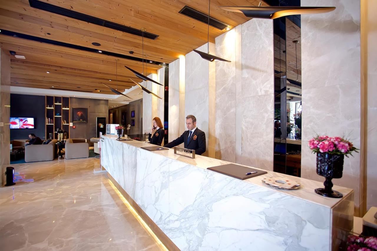 ดอสโซ่ ดอสซี่ โฮเต็ล แอน์ สปา ดาวน์ทาวน์ Hotel อิสตันบูล ภายนอก รูปภาพ The photo shows a hotel lobby reception area. The reception desk is elegantly designed with a marble surface and is situated against a backdrop of light-colored walls. There are two staff members behind the desk—one is a man in a suit, and the other 