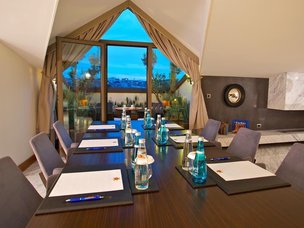 ดอสโซ่ ดอสซี่ โฮเต็ล แอน์ สปา ดาวน์ทาวน์ Hotel อิสตันบูล ภายนอก รูปภาพ The photo shows a conference room setup. There is a long wooden table with several chairs arranged around it. On the table, there are notebooks or notepads, pens, and bottles of water, all placed neatly. The room features large windows with curtains,
